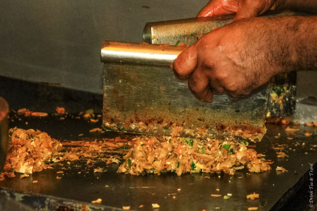 Cook chopping ingredients on a hot griddle in a Sri Lankan kitchen